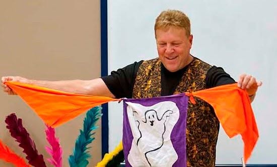 image of magician Glen Girard performing a magic trick with brightly colored hankerchiefs